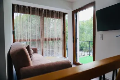 a living room with a couch and a large window at HANA Superior Apartment in Kakanj