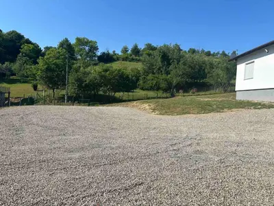 a large gravel driveway with a white building and trees at Vila Fina in Laktaši