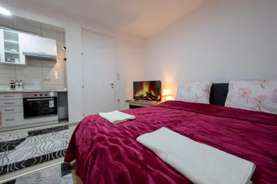 a bedroom with a large purple bed with a fireplace at Apartmani Božur in Bosanska Gradiška