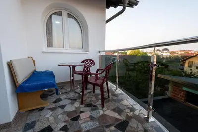a balcony with a table and chairs and a window at Apartmani Božur in Bosanska Gradiška