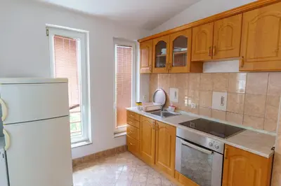 a kitchen with wooden cabinets and a white refrigerator at Motel Aqua Kozarac in Kozarac
