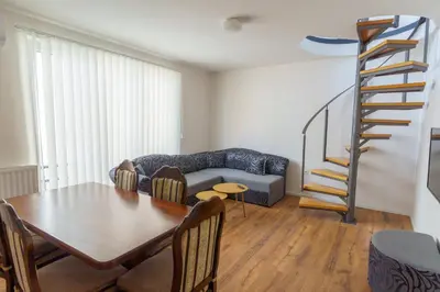 a living room with a table and a spiral staircase at Motel Aqua Kozarac in Kozarac