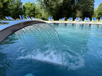 a pool with a fountain in the water with chairs at Apartman Hanna