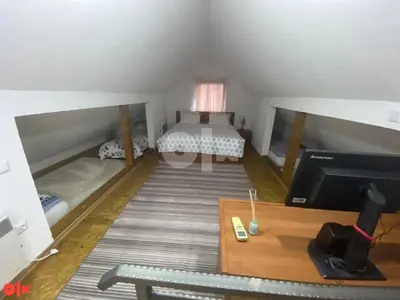 a small attic room with a bed and a television at Vikendica Sarah in Tuzla