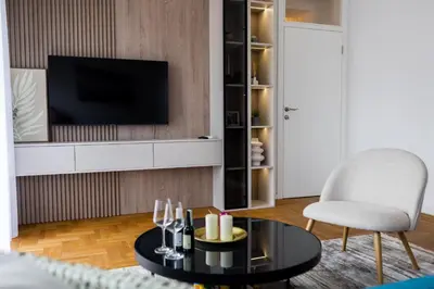 a living room with a tv and a table and a chair at Polza in Banja Luka