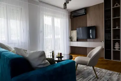 a living room with a blue couch and a tv at Polza in Banja Luka