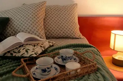 a basket with two cups and a book on a bed at Ćeif HOUSE in Bihać