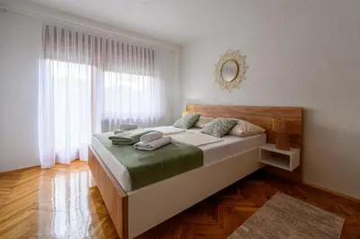 a bedroom with a large bed with a large window at Apartman HAAN in Bihać