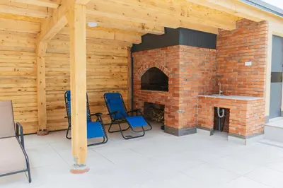 a patio with a brick fireplace and two blue chairs at Hafizove ville na Uni in Illidža