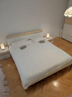 a large white bed in a room with two lights at Apartman Doma in Livno