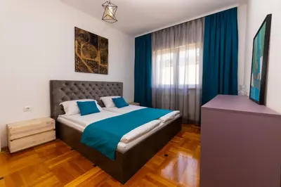 a bedroom with a bed with blue sheets and a window at Khalilah Apartment 3 in Bihać