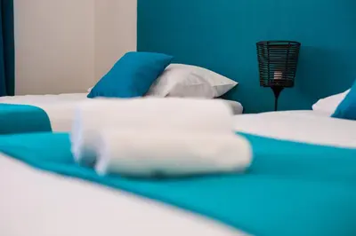 a bed with blue and white sheets and pillows at Khalilah Apartment 3 in Bihać
