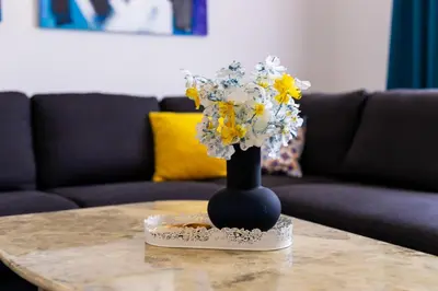 a black vase with yellow and white flowers on a table at Khalilah Apartment 3 in Bihać