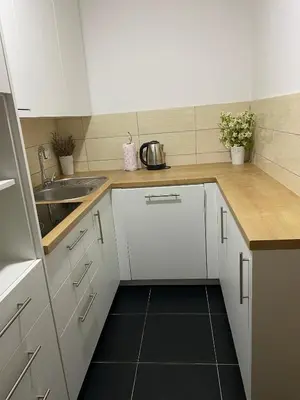a kitchen with white cabinets and a black floor at Apartment Boky in Livno