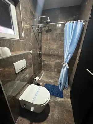 a bathroom with a shower with a toilet and a shower curtain at Apartmani M&DŽ Bihać in Bihać