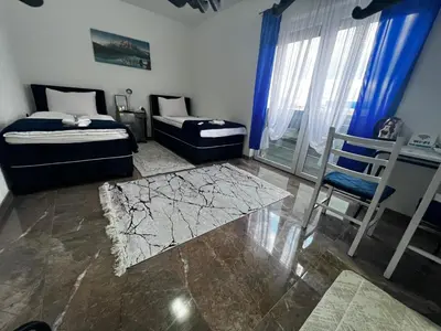 a bedroom with two beds and a table and a chair at Apartmani M&DŽ Bihać in Bihać