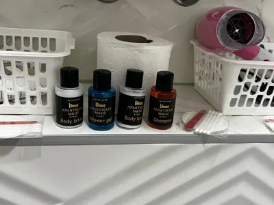 a shelf with four bottles of paint and a roll of toilet paper at Apartmani M&DŽ Bihać in Bihać
