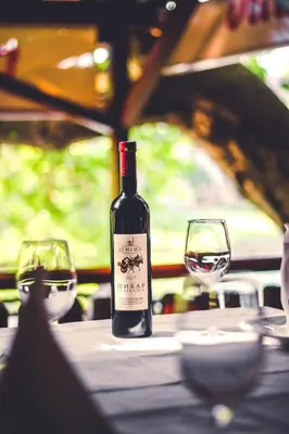 a bottle of wine sitting on a table with two glasses at Hotel Vila Vrbas in Banja Luka