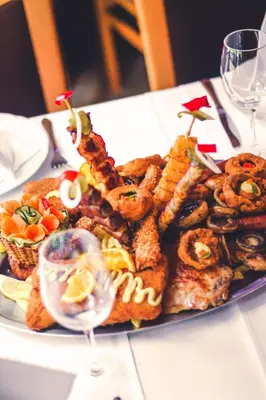 a plate of food with meat and other foods on a table at Hotel Vila Vrbas in Banja Luka