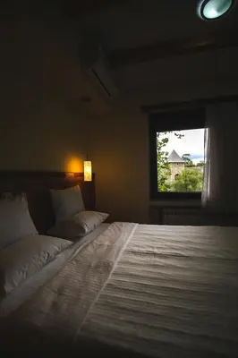 a bedroom with a large white bed with a window at Hotel Vila Vrbas in Banja Luka