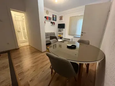 a living room with a glass table and chairs at Apartman Serdjo