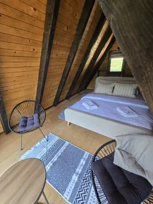 a room with a bed and two chairs in a attic at JAGI Bungalovi Mrkonjic Grad in Mrkonjić Grad