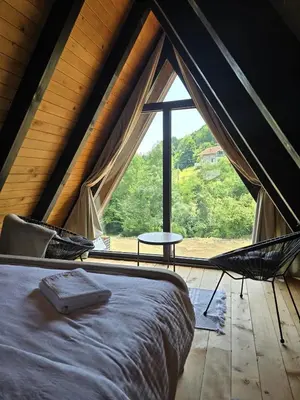 a bed in a room with a large window at JAGI Bungalovi Mrkonjic Grad in Mrkonjić Grad