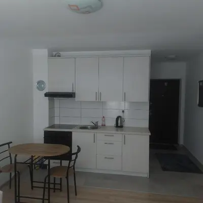 a kitchen with white cabinets and a table and chairs at Apartman Mario in Tomislavgrad