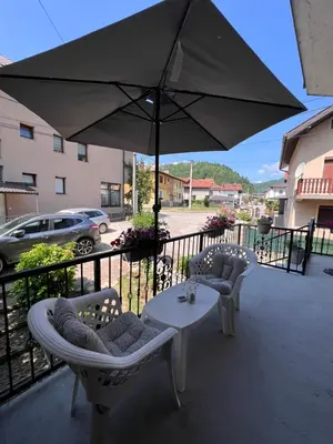 a patio with a table and chairs and an umbrella at Apartmani Odmor Fojnica in Fojnica