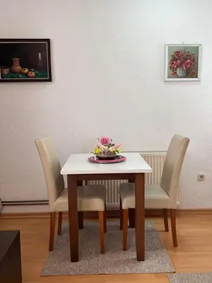 a table with chairs and a plate of flowers on it at Apartmani Odmor Fojnica in Fojnica