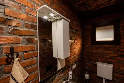 a bathroom with a mirror and a brick wall at Etno Camp Lucić in Odžak