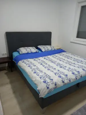 a bedroom with a bed with a blue and white comforter at Stan Živinice bb in Živinice