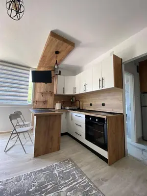 a kitchen with white cabinets and a table and a chair at Stay for 2 in Jajce