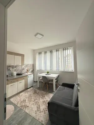 a living room with a couch and a table in a kitchen at Apartman EM Bugojno in Bugojno