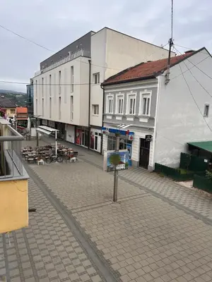 a street with a white building and tables and chairs at Apartman EM Bugojno in Bugojno