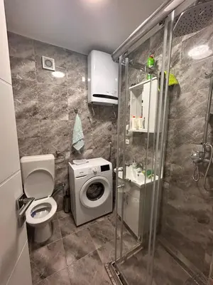 a bathroom with a shower and a washing machine at Apartman EM Bugojno in Bugojno