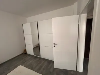 a white wardrobe in a room with a mirror at Apartman EM Bugojno in Bugojno