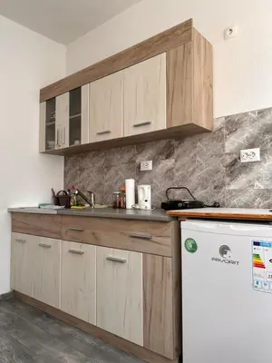 a kitchen with wooden cabinets and a white refrigerator at Apartman EM Bugojno in Bugojno