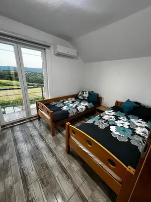 two beds in a room with a large window at Villa Melek in Bihać