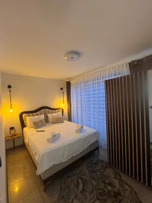 a bedroom with a bed with white sheets and a window at Apartman Booem in Bihać