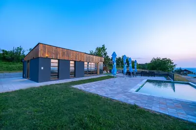 a building with umbrellas next to a swimming pool at Vila Natalijina Ramonda in Banja Luka