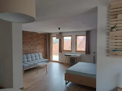 a living room with a bed and a couch and a brick wall at Guest House Puccallpah in Visoko