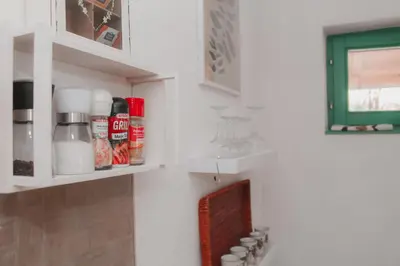 a kitchen with white cabinets and a shelf with spices at Holiday Home Tunnel Ravne in Visoko