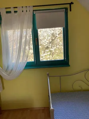 a bedroom with a window with white curtains and a bed at Holiday Home Tunnel Ravne in Visoko