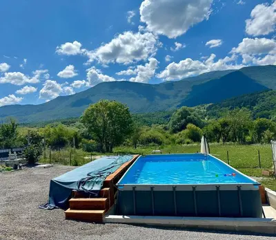 a large swimming pool with mountains in the background at Tiny House Ljiljan in Bihać
