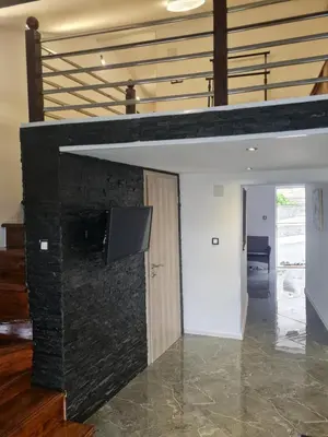 a stone fireplace in a living room with a staircase at Apartman hukanovic in Bosanska Krupa