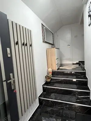 a hallway with black tiled stairs with a refrigerator at Stan na dan Apartman Durakovic in Cazin