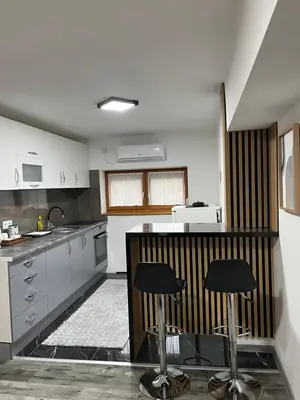 a kitchen with two bar stools in the middle at Stan na dan Apartman Durakovic in Cazin