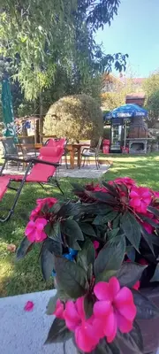 a group of chairs and pink flowers in a yard at Stan na dan Apartman Durakovic in Cazin
