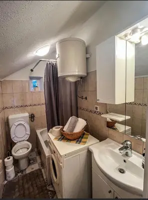 a bathroom with a sink and a toilet and a mirror at Stan na dan Apartman Durakovic in Cazin